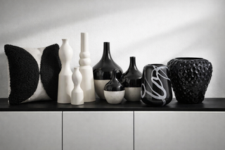 Vasen in weiß und schwarz, schwarz -weißes Kissen auf schwarz weißem Schrank