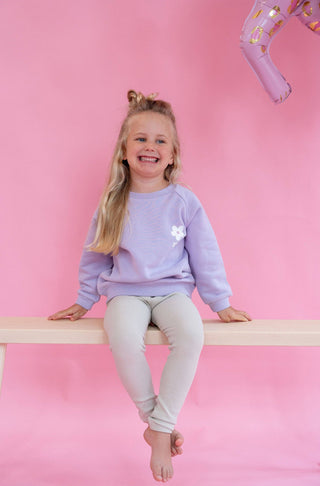 Lilafarbener Kinderpullover mit einer schönen weißen Blume im Brustbereich