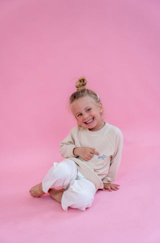 Kinderpullover in beige mit blauen herzchen die sich an der Hand halten 