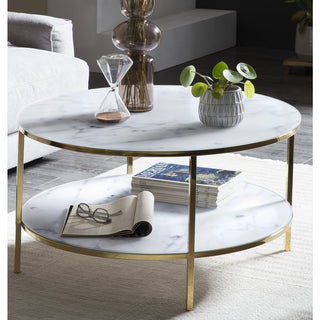 marmor tisch grau mit zwei ebenen, goldene metallbeine, bucher, brille, pflante vase , sofa im hintergrund, beiger teppich