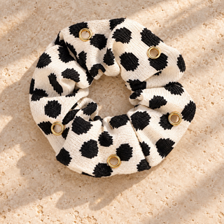 Cremefarbener Scrunchie mit unregelmäßigen schwarzen Tupfen und sechs goldfarbenen Ösen, ohne Charms.
