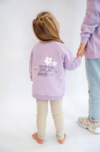 Pullover in hellen lila mit Growing side by side aufschrift und Gänseblümchen