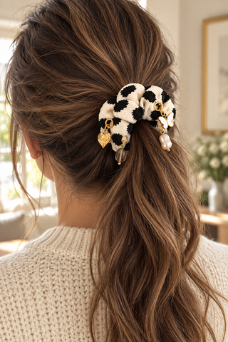 Scrunchie „Black Dots“ in Creme mit schwarzen Tupfen und verschiedenen Charms, in einem braunen Pferdeschwanz getragen.