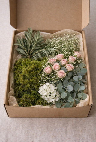 Karton mit verschiedene Blumen wie Moos, Eukalyptus, Schleierkraut, Rosa rosen, grauer Hintergrund