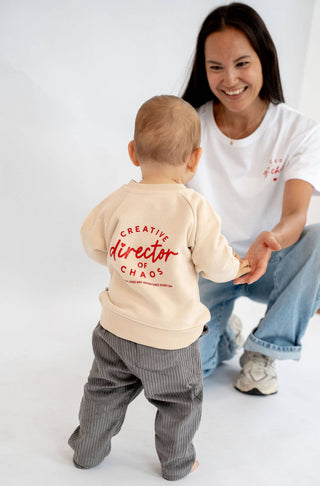Pullover für Babys und Kids in beige mit schöner roter Schrift Creative director of chaos. Die Mutter trägt das passende T-Shirt in weiß mit der Aufschrift Club of chaos