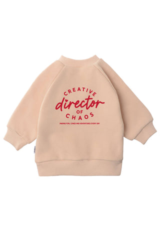 Pullover in beige von hinten Sichtbar mit der Aufschrift in rot Creative director of chaos. 