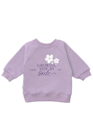 Pullover in Lila für Kinder mit der Aufschrift Growing side by side und weißen Gänseblümchen